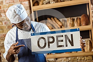 handsome african american baker pointing at open sign