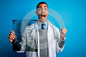 Handsome african american doctor man wearing stethoscope holding chest xray screaming proud and celebrating victory and success