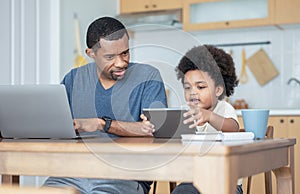 Handsome African American father using laptop computer and his cute little boy using digital tablet learning online, watching
