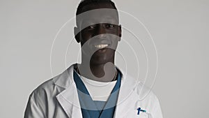 Handsome African American male doctor looking happy smiling on camera over white background