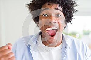 Handsome african american man with afro hair excited for success with arms raised celebrating victory smiling