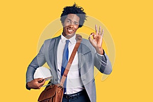 Handsome african american man with afro hair holding architect hardhat doing ok sign with fingers, smiling friendly gesturing