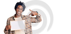 Handsome african american man with afro hair holding blank empty banner pointing finger to one self smiling happy and proud