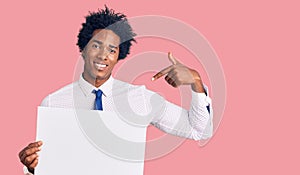 Handsome african american man with afro hair holding blank empty banner pointing finger to one self smiling happy and proud