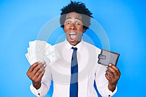 Handsome african american man with afro hair holding wallet and dollars banknotes celebrating crazy and amazed for success with