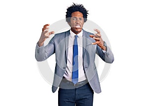 Handsome african american man with afro hair wearing business jacket shouting frustrated with rage, hands trying to strangle,