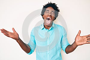 Handsome african american man with afro hair wearing casual clothes celebrating mad and crazy for success with arms raised and