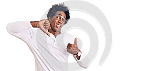 Handsome african american man with afro hair wearing casual clothes and glasses doing thumbs up and down, disagreement and