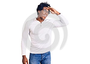 Handsome african american man with afro hair wearing casual clothes and glasses very happy and smiling looking far away with hand