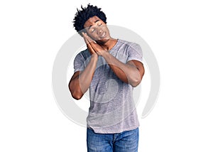 Handsome african american man with afro hair wearing casual clothes sleeping tired dreaming and posing with hands together while