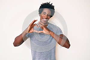 Handsome african american man with afro hair wearing casual clothes smiling in love doing heart symbol shape with hands