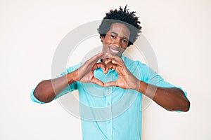 Handsome african american man with afro hair wearing casual clothes smiling in love doing heart symbol shape with hands