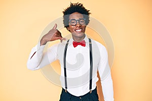 Handsome african american man with afro hair wearing hipster elegant look smiling doing phone gesture with hand and fingers like