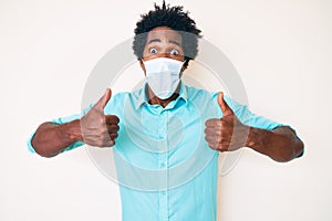 Handsome african american man with afro hair wearing medical mask celebrating crazy and amazed for success with open eyes