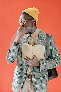 handsome african american man with book eating apple