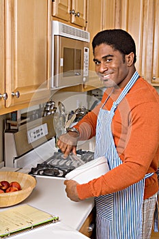 Handsome African-American man cooks in kitchen