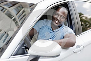 Handsome african american man driving car, shot from outside