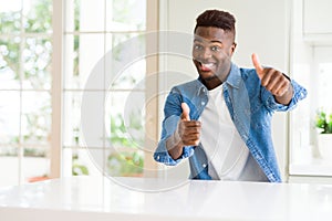 Handsome african american man at home approving doing positive gesture with hand, thumbs up smiling and happy for success