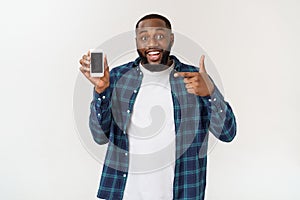 Handsome african american man isolated on grey background, presenting smart phone.