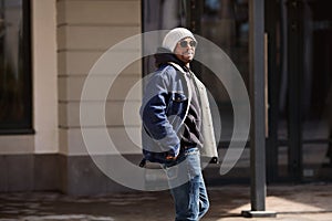 Handsome African american man model wearing stylish outfit denim jacket, hat, hoodie and sunglasses walking in city