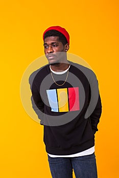 Handsome African American man posing in black sweatshirt on a yellow background. Youth street fashion photo with afro