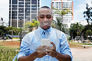 Handsome african american man sending text message with smartphone