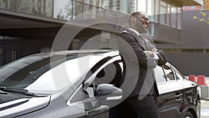 Handsome African American man sincerely smiling staying near his car, good news