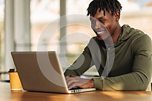 Handsome African American man is typing on a laptop while sitting in a cafe. young student on distance learning at home