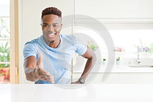 Handsome african american man wearing casual t-shirt at home smiling friendly offering handshake as greeting and welcoming