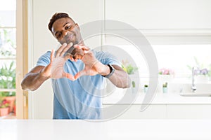 Handsome african american man wearing casual t-shirt at home smiling in love showing heart symbol and shape with hands