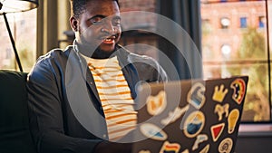 Handsome African American Man Working from Home on Laptop Computer in Sunny Stylish Loft Office