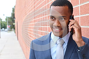 Handsome African American modern businessman walking in town and calling on mobile phone