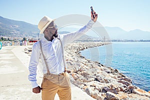 Handsome african american person casual fashion look outfit in straw hat,white shirt walking by Tyrkey coast making