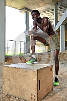 Handsome African American sportman standing on the street while taking break after training. Black male having rest