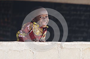 Handsome African Baby Boy Laughing Behind Wall at School