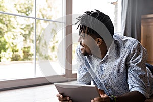 Handsome African guy lying on floor indoor with digital tablet