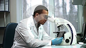 Handsome African male scientist using a microscope while working at the research laboratory