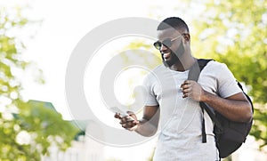 Handsome african man with backpack textmessaging on phone