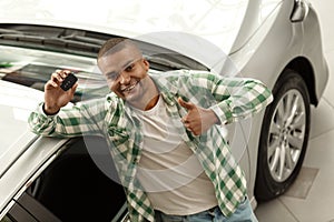Handsome African man choosing new car at dealership