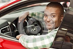 Handsome African man choosing new car at dealership