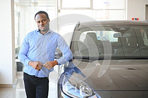 Handsome African man choosing a new car at the dealership