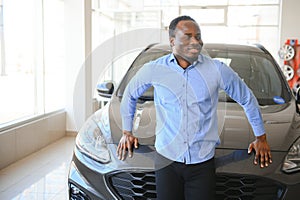 Handsome African man choosing a new car at the dealership