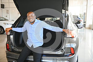 Handsome African man choosing a new car at the dealership