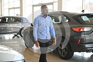 Handsome African man choosing a new car at the dealership