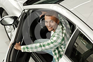 Handsome African man choosing new car at dealership