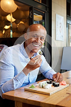 Handsome african man eating sushi