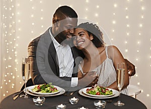 Handsome african man hugging his girlfriend while festive dinner