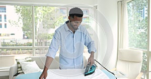 Handsome African man ironing white bath towels