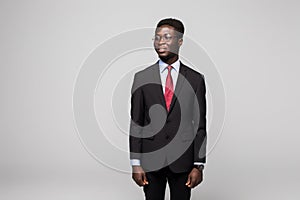 Handsome African man looking away while standing against grey background