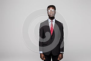 Handsome African man looking at camera while standing against grey background